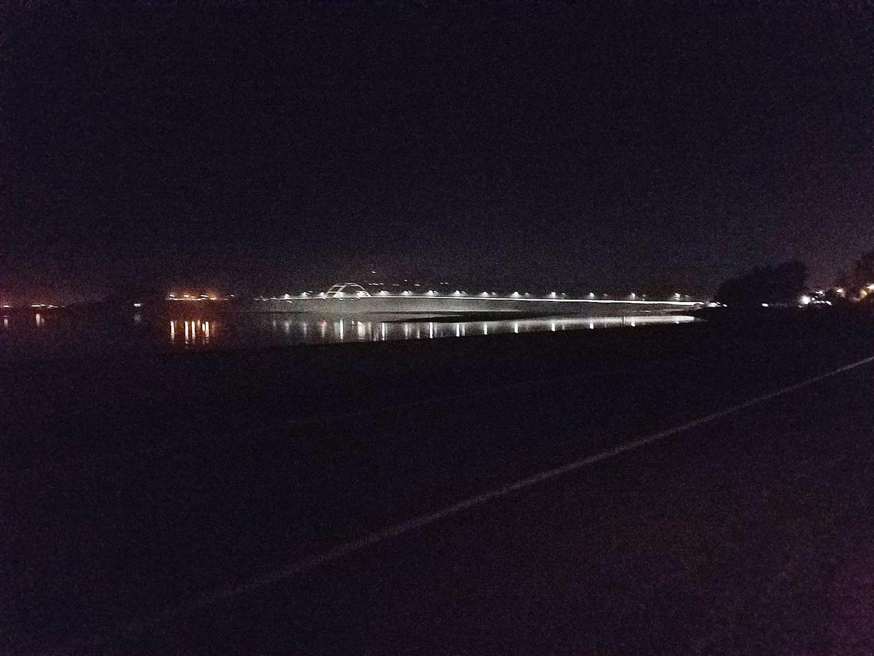 A nighttime view of a bridge with lights reflecting on the water.