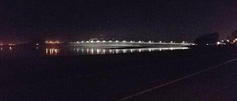 A nighttime view of a bridge with lights reflecting on the water.