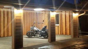 A motorcycle parked in a covered garage with wooden walls and a concrete floor. - The Waldport Inn (Waldport)