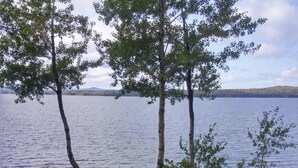 Järvenrantainen piknikalue, jossa on nuotiopaikka, kaksi Adirondack-tuolia ja piknikpöytä.
