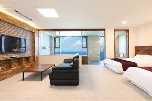 A modern hotel room with a TV, a sofa, a bed, and a balcony with a sea view. - Poolvilla K (Gangneung)
