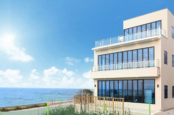A modern building with a balcony overlooking the sea. - Poolvilla K (Gangneung)