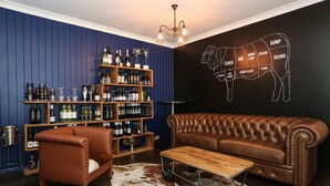 A room with a brown leather sofa, a wooden coffee table, a cowhide rug, and a wall with a butcher's diagram. - Clermont Country Motor Inn (Clermont)