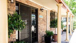 A reception area with a brick facade, a metal gate, and potted plants. - Clermont Country Motor Inn (Clermont)