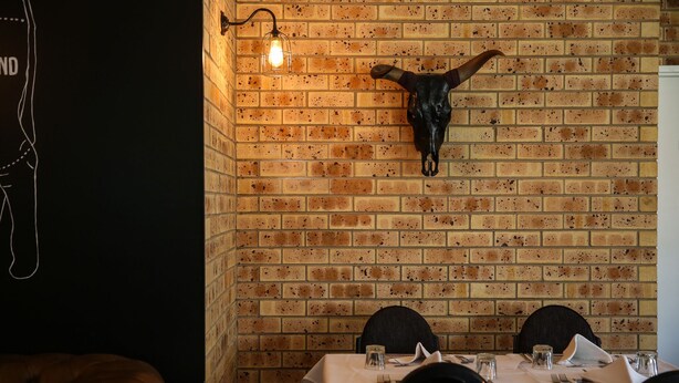 A brick wall with a mounted cow skull and a hanging light fixture. - Clermont Country Motor Inn (Clermont)