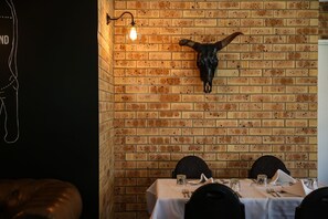 A brick wall with a mounted cow skull and a hanging light fixture. - Clermont Country Motor Inn (Clermont)