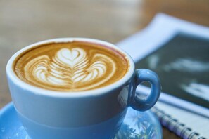 A cup of coffee with latte art on a saucer. - Clermont Country Motor Inn (Clermont)