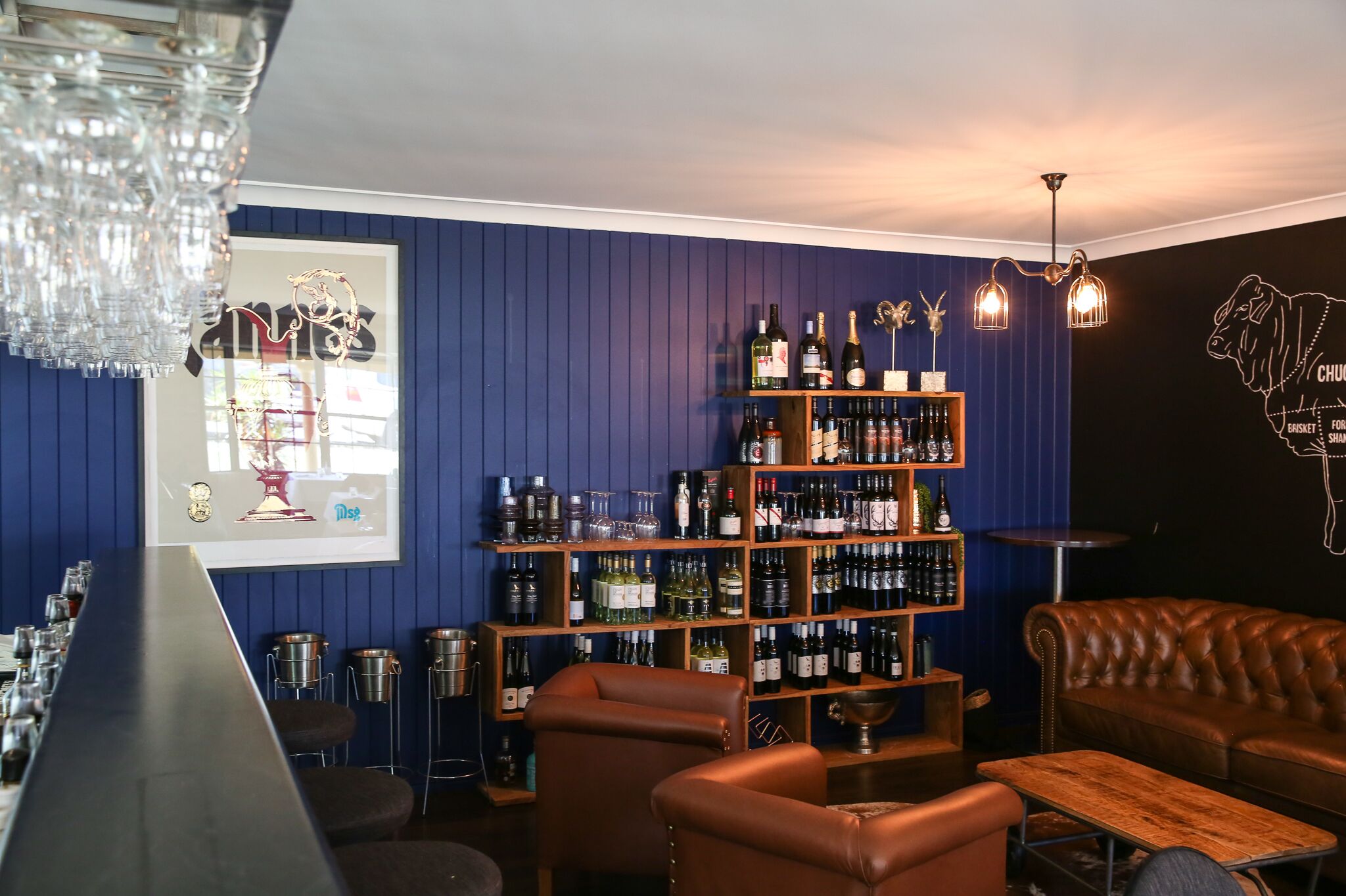 Una zona de bar con una bodega, asientos de cuero y un candelabro.