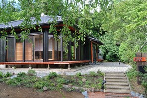 A traditional Japanese-style building with large sliding doors, a wooden deck, and a gravel pathway leading to the entrance. - Lodge365 (Katsuura)