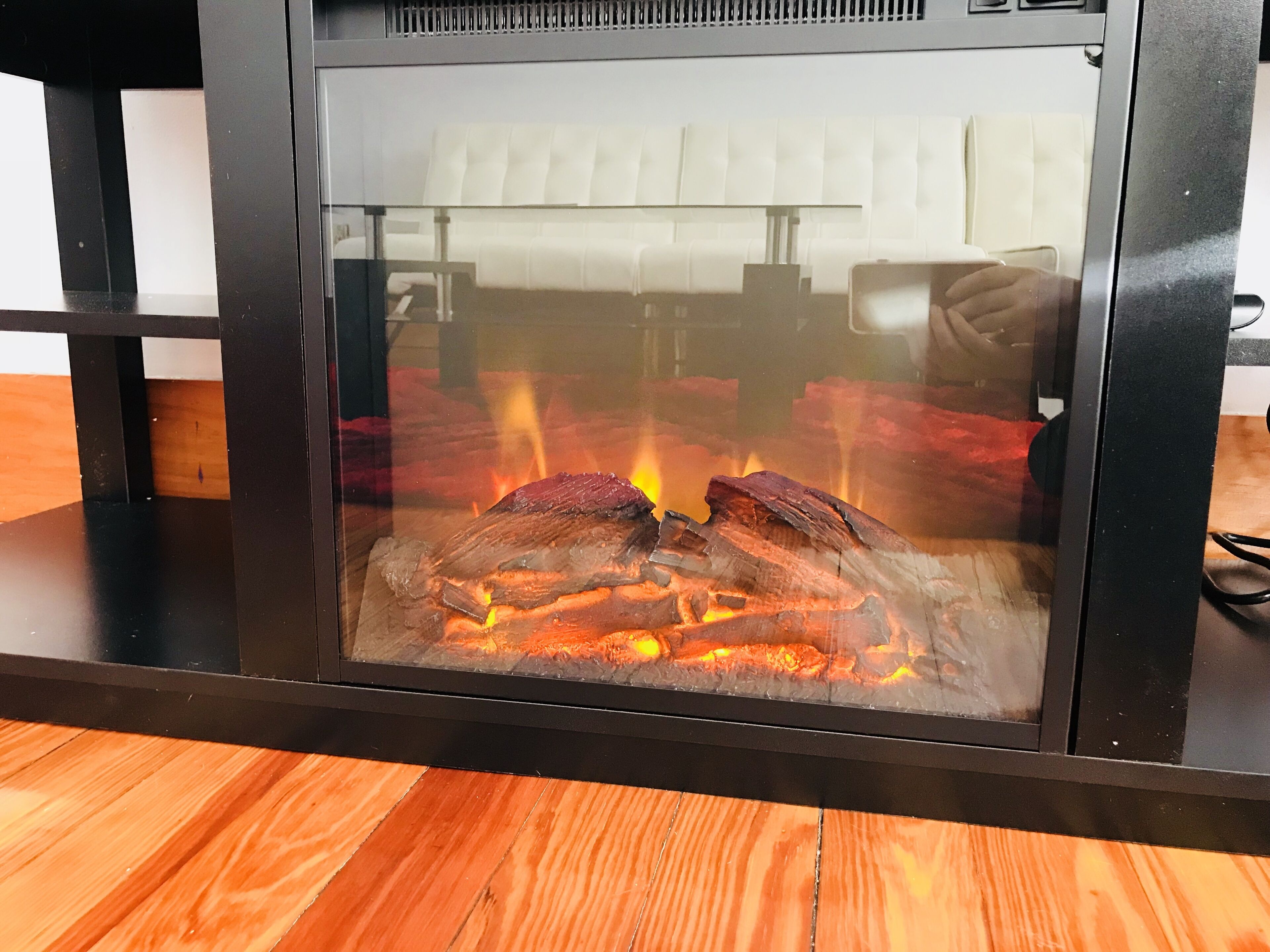 Chimenea de vidrio con leña ardiendo a la vista.