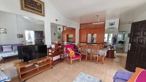 A living room with a television, sofa, dining table, and chairs. - Spacious apt with sea and pool views 2 bedrooms, wifi (Puerto del Carmen)