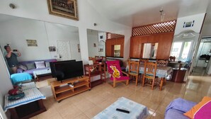 A living room with a TV, sofa, chairs, and a dining area with a table and chairs. - Spacious apt with sea and pool views 2 bedrooms, wifi (Puerto del Carmen)
