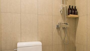 A bathroom with a toilet, a shower, and a shelf with toiletries.