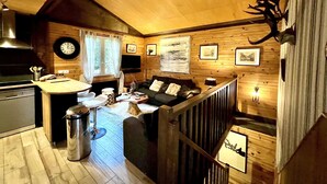 A cozy cabin interior with a wooden interior, a dining area, a sofa, a clock, and a mounted animal head. - Dream cottage in the heart of nature: forest, river, cabin atmosphere & wood stove (Xonrupt-Longemer)