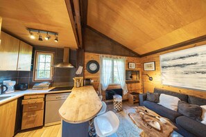 A cozy cabin interior with a kitchen, dining area, and living space. - Dream cottage in the heart of nature: forest, river, cabin atmosphere & wood stove (Xonrupt-Longemer)