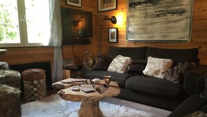 A cozy living room with a dark grey sofa, a wooden coffee table, and a fluffy white rug. - Dream cottage in the heart of nature: forest, river, cabin atmosphere & wood stove (Xonrupt-Longemer)