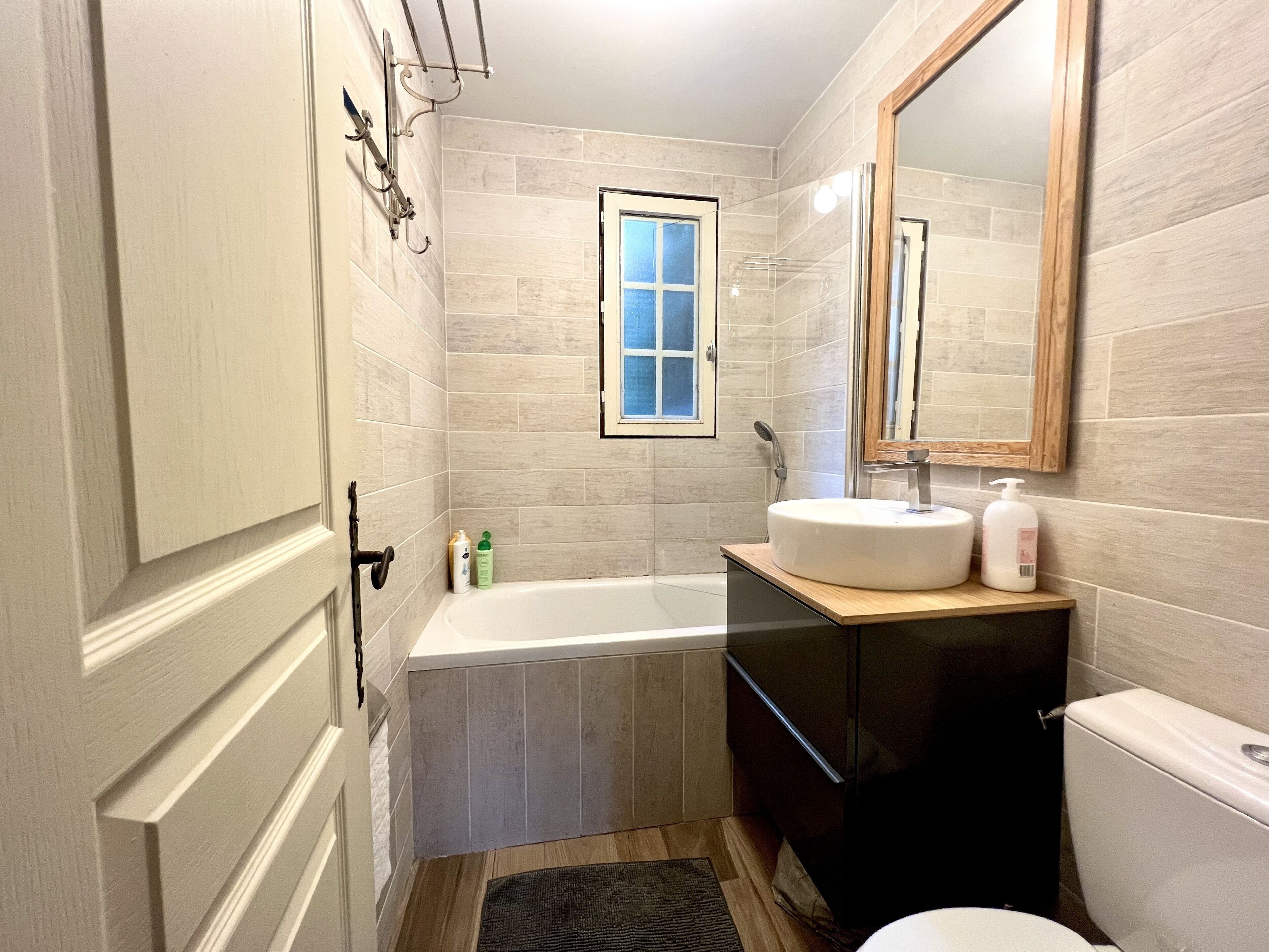 A bathroom with a bathtub, a sink, a toilet, and a window.