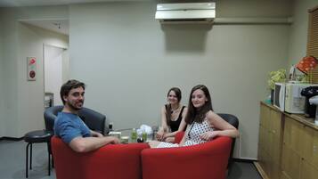 A room with a dining table, red chairs, a microwave, and a cabinet with storage drawers.