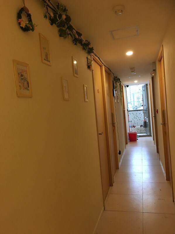 A narrow hallway with doors on both sides, decorated with wall-mounted pictures and a garland.