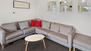A modern living room with a grey sectional sofa, a white coffee table, and a framed artwork on the wall. - Ski View 4 (Mount Buller)