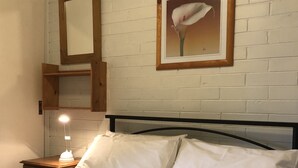 A bed with white bedding, a nightstand with a lamp, and a framed picture of a flower on the wall. - Snowflake 14 (Mount Buller)