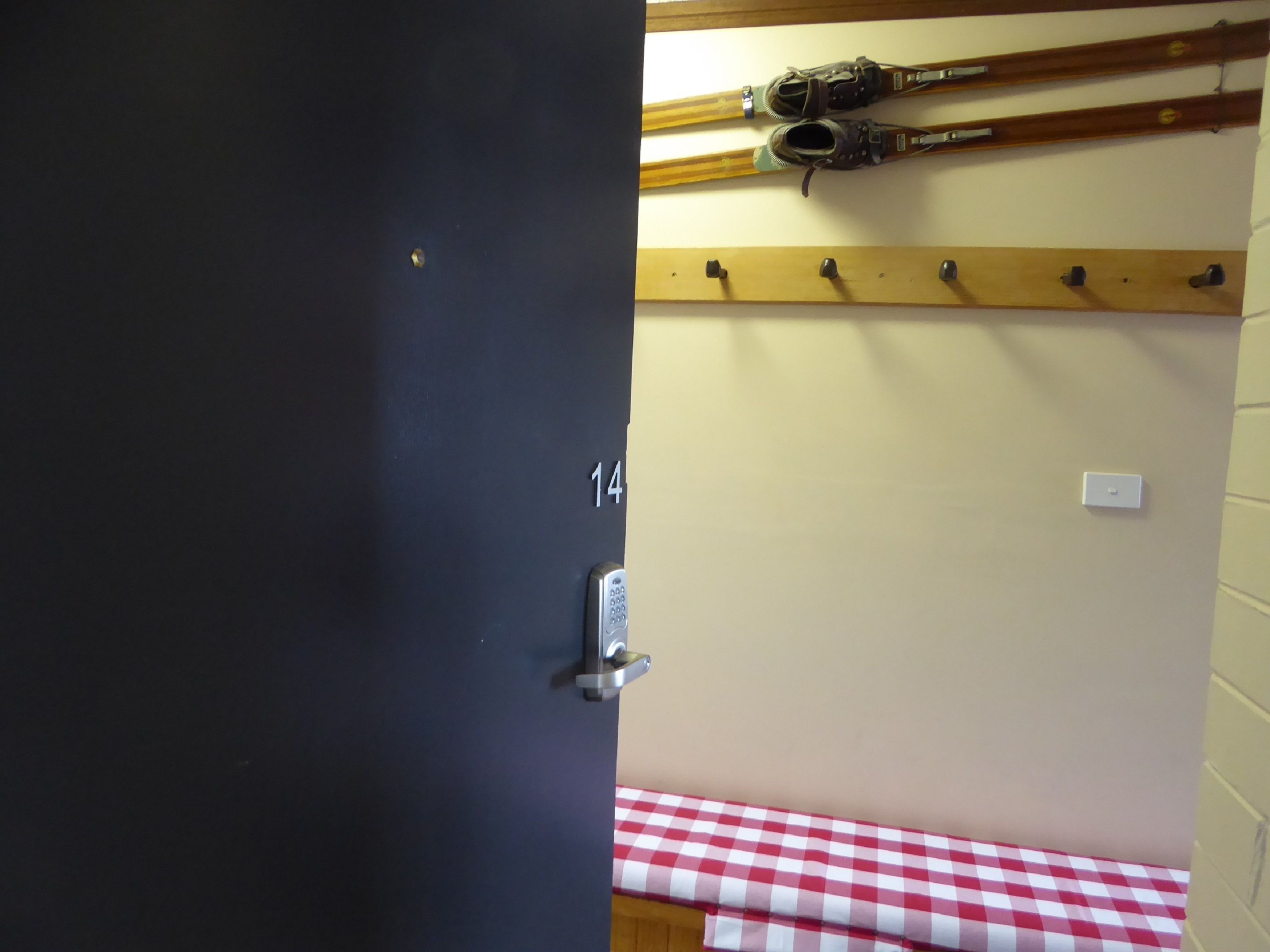 A room with a checkered table, a door with a number, and skis on a rack.