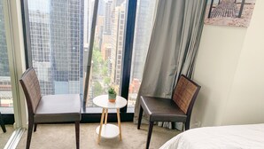 A hotel room with two chairs, a small round table with a potted plant, and a bed. - Sunshine Boutique Apartments Collins (Melbourne)
