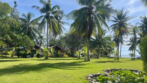 A tropical resort with palm trees, a well-maintained lawn, and a small pond with lily pads. - Malai Asia Resort (Thap Sakae)