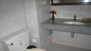A bathroom with a toilet, sink, and a vase with flowers on the countertop. - Malai Asia Resort (Thap Sakae)