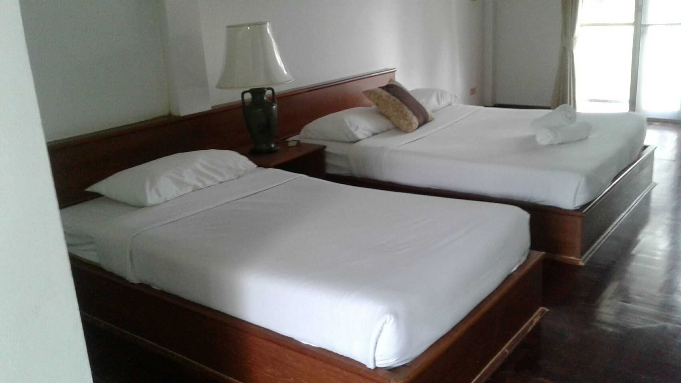 Two single beds with wooden headboards and white bedding in a hotel room.