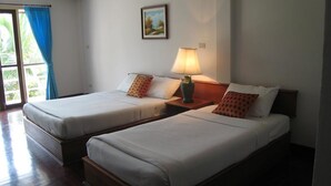 A hotel room with two beds, a nightstand with a lamp, a painting on the wall, and a window with blue curtains. - Malai Asia Resort (Thap Sakae)