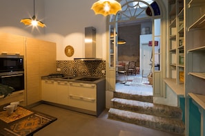 Een moderne keuken met een magnetron, oven en een decoratieve spatwand. Er is een eethoek met een tafel en stoelen, en een trap die naar een andere kamer leidt.