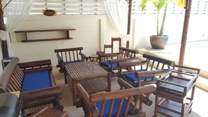 A covered outdoor seating area with wooden furniture and a sign reading "SABAT".