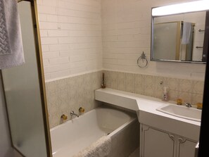 A bathroom with a bathtub, a sink, and a mirror. - Snowflake 16 (Mount Buller)
