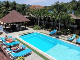 Una piscina al aire libre, sillones reclinables de piscina