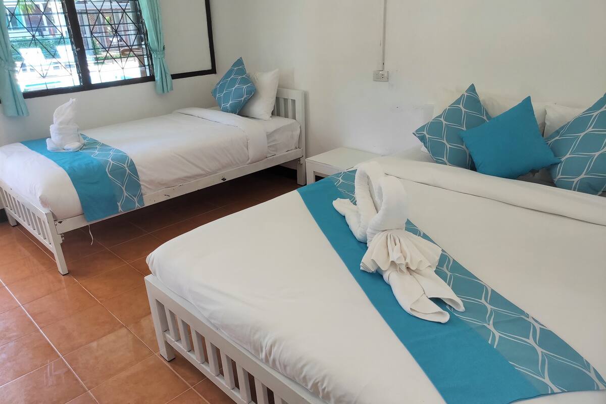 A hotel room with two beds, each with a white and blue bedspread, and matching pillows.