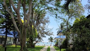 A pathway leading to a beach with a clear view of the sea, surrounded by lush greenery and trees. - Assava Dive Resort (Koh Tao)