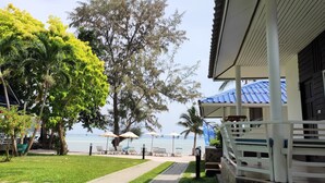 A beachfront property with a covered patio, lounge chairs, and a view of the sea. - Assava Dive Resort (Koh Tao)