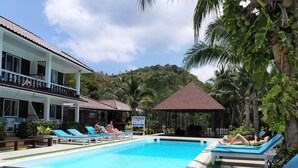A pool area with lounge chairs, a gazebo, and a building with a balcony. - Assava Dive Resort (Koh Tao)