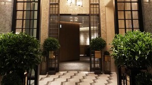 A lobby with a geometric patterned floor, a central chandelier, and symmetrical wall panels.