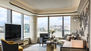 A modern living room with a large TV, comfortable seating, a coffee table, and a city view. - Hyatt Centric Victoria Harbour Hong Kong (Hong Kong)