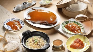 Una mesa con un pato asado entero, varios platos y una olla humeante.