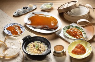 Una mesa con un pato asado entero, varios platos y una olla humeante.