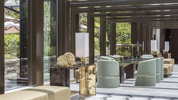 Un moderno espacio lounge al aire libre con una mesa de vidrio, asientos acolchados e iluminación ambiental.