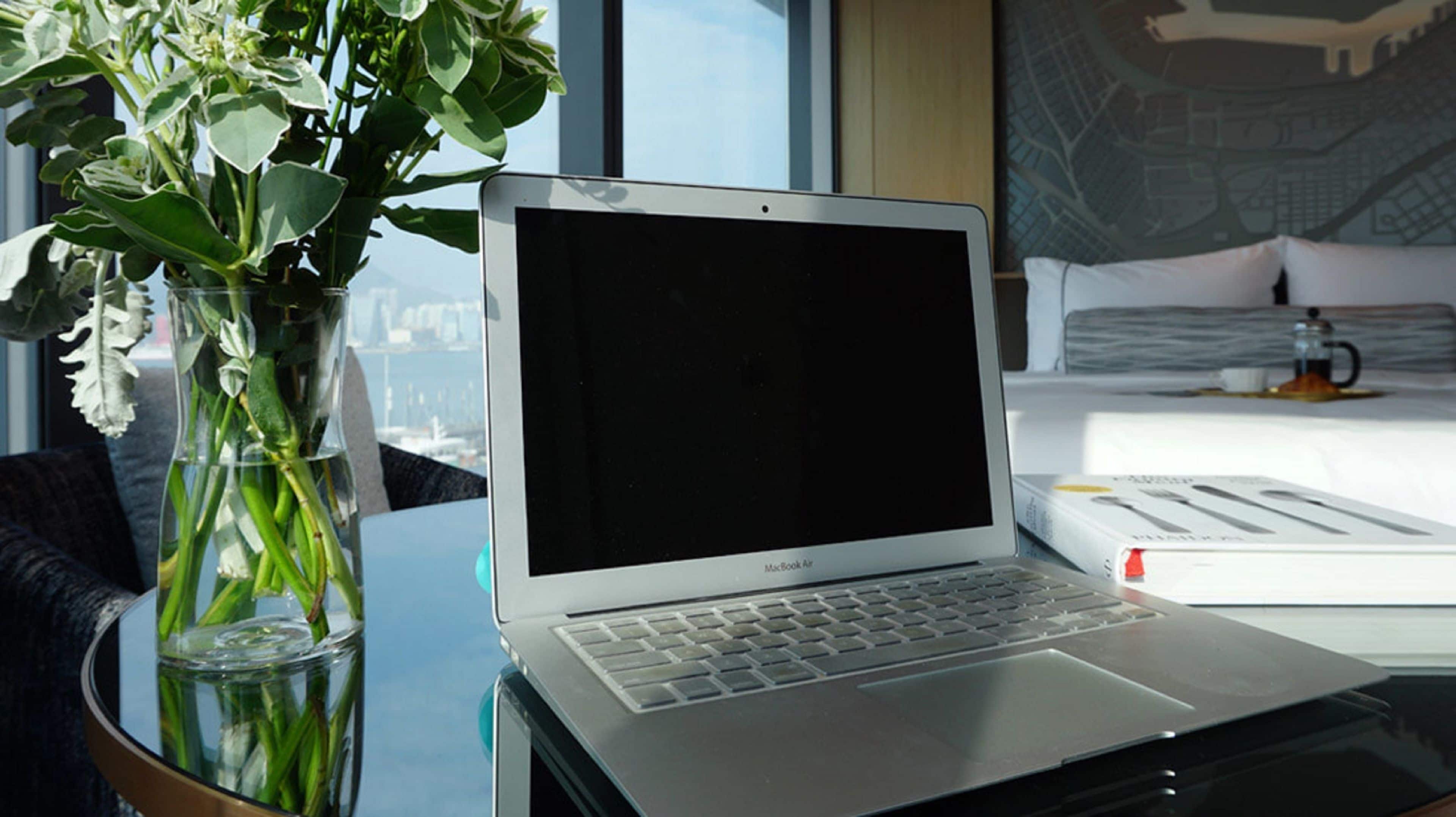 Un MacBook Air sobre un escritorio, con una vista despejada de un paisaje urbano a través de una ventana.