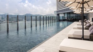 A rooftop infinity pool with lounge chairs and umbrellas, overlooking a cityscape. - Hyatt Centric Victoria Harbour Hong Kong (Hong Kong)