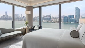 A modern hotel room with a large bed, a seating area, and a view of a city skyline and water. - Hyatt Centric Victoria Harbour Hong Kong (Hong Kong)