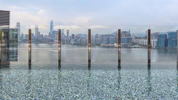 Una piscina infinita con vistas a la ciudad, con edificios altos y una extensión de agua.