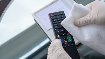 A person holding a remote control with a message about keeping it clean.