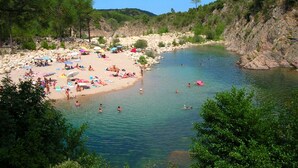 A beach with clear water, people swimming and sunbathing, and a rocky landscape in the background. - Standing Apartment, Facing the Sea! (Ghisonaccia)